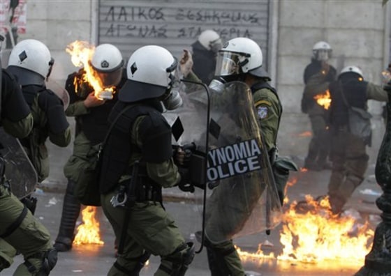 Riot policemen's clothing catches fire after protesters threw gasoline bombs during at them Thursday during clashes in Athens.